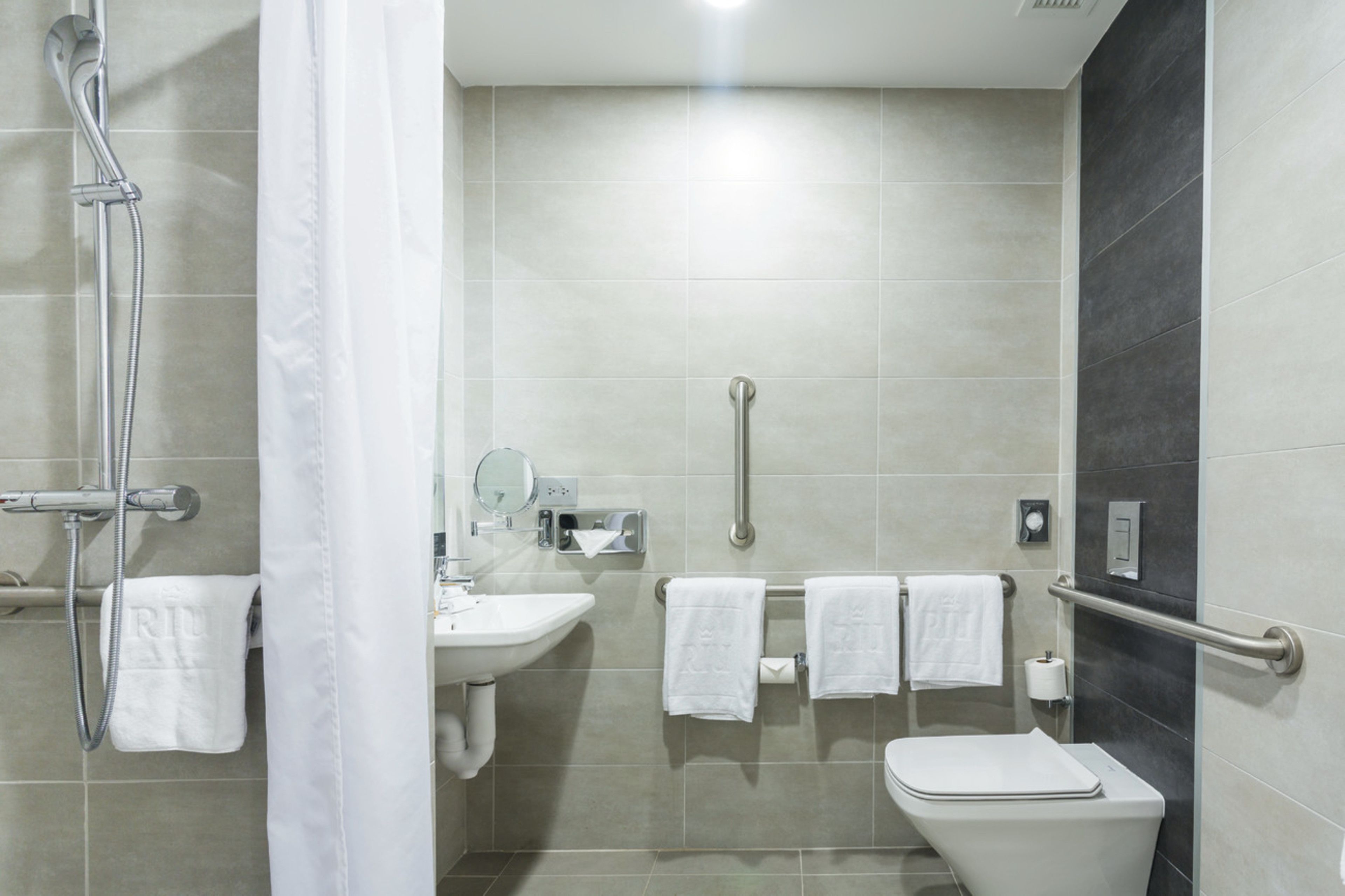 A modern bathroom with a shower, sink, and toilet.