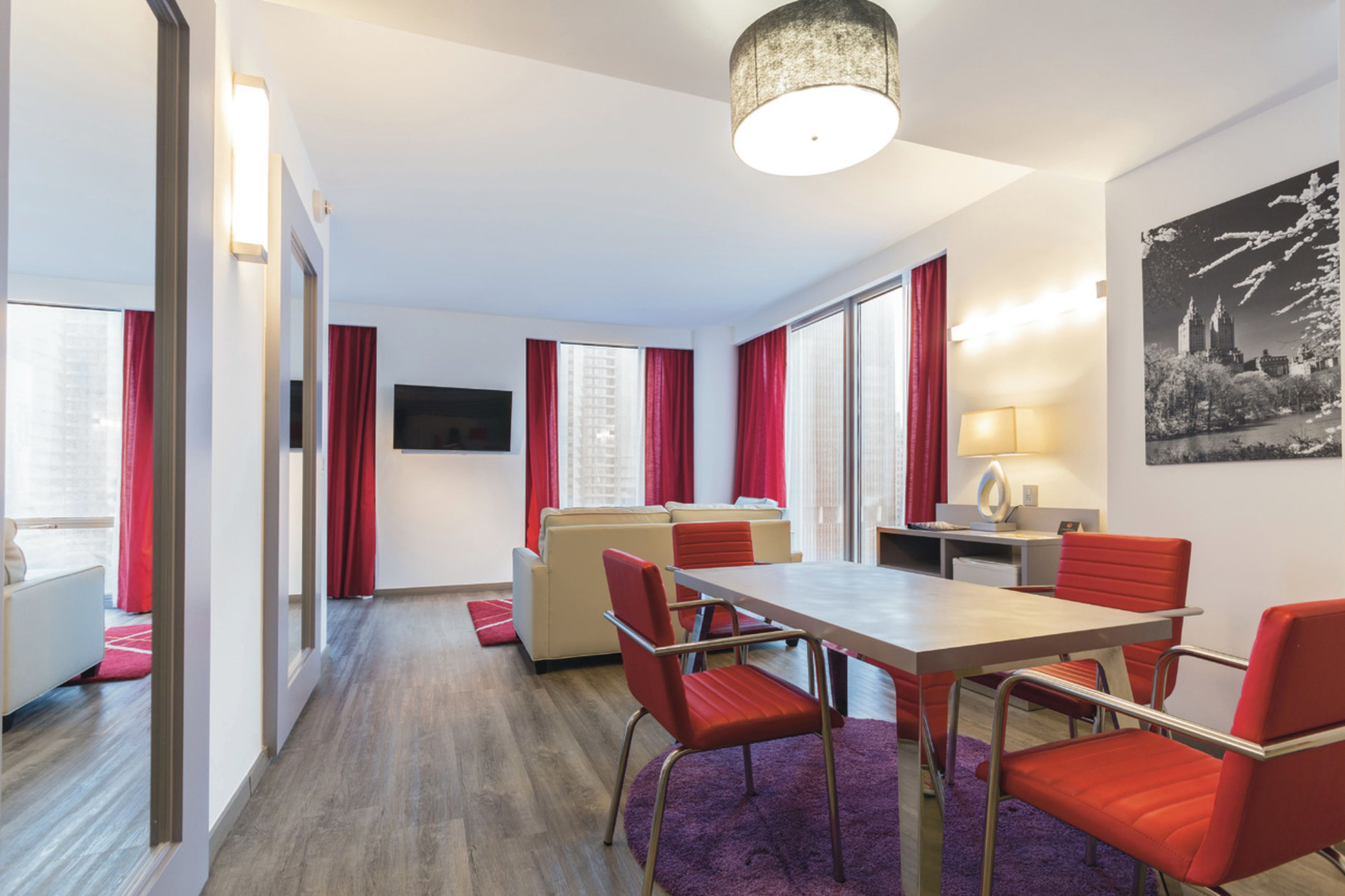 Une chambre d’hôtel moderne dotée d’un coin repas, d’un canapé et d’une télévision.