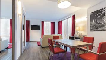 Une chambre d’hôtel moderne dotée d’un coin repas, d’un canapé et d’une télévision.