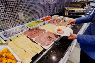 Egy svédasztal, ahol különféle ételek – köztük húsok, sajtok és gyümölcsök – választhatóak.