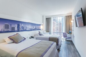 Een hotelkamer met twee bedden, een bureau, een stoel, een stadsgezicht muurschildering en een televisie aan de muur.