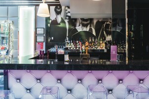 Een barruimte met verschillende drankflessen, een bargedeelte en een zithoek met comfortabele stoelen.