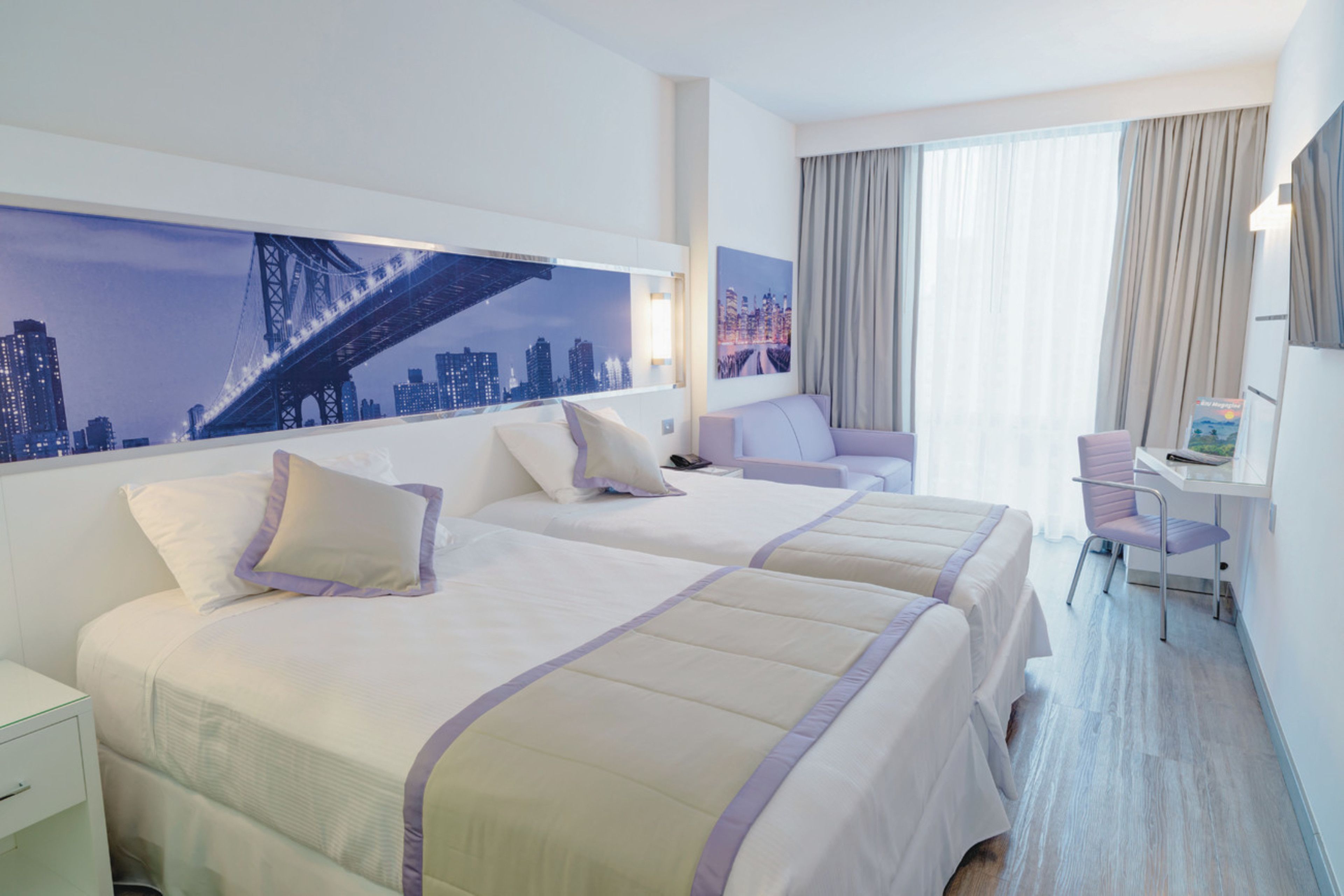 Habitación de hotel con dos camas, un escritorio y una silla.