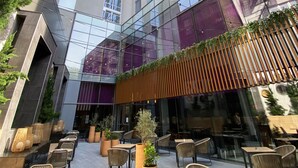 A modern building with a glass facade, outdoor seating area with wicker chairs and tables, and a mix of indoor and outdoor spaces. - Hotel Riu Plaza New York Times Square (New York)