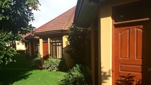A residential building with a red-tiled roof, a wooden door, and a well-maintained lawn with various plants. - Ahadi Lodge (Arusha)