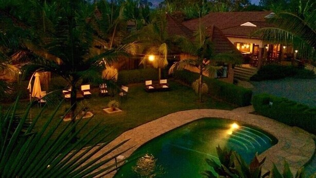 A resort with a swimming pool, lounge chairs, and a mountain in the background. - Ahadi Lodge (Arusha)