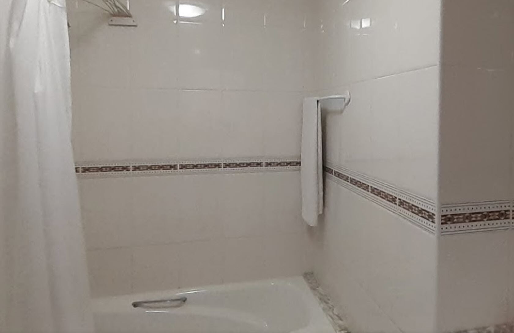 Un baño con bañera, toallero y detalles decorativos en cerámica.