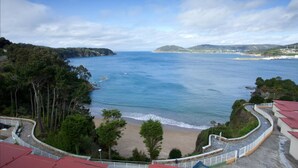 A coastal view with a beach, trees, and a clear sky. - Apartamentos Las Sirenas (Viveiro)