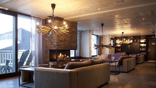 Una sala de estar acogedora con chimenea de piedra, luminarias modernas y asientos cómodos.