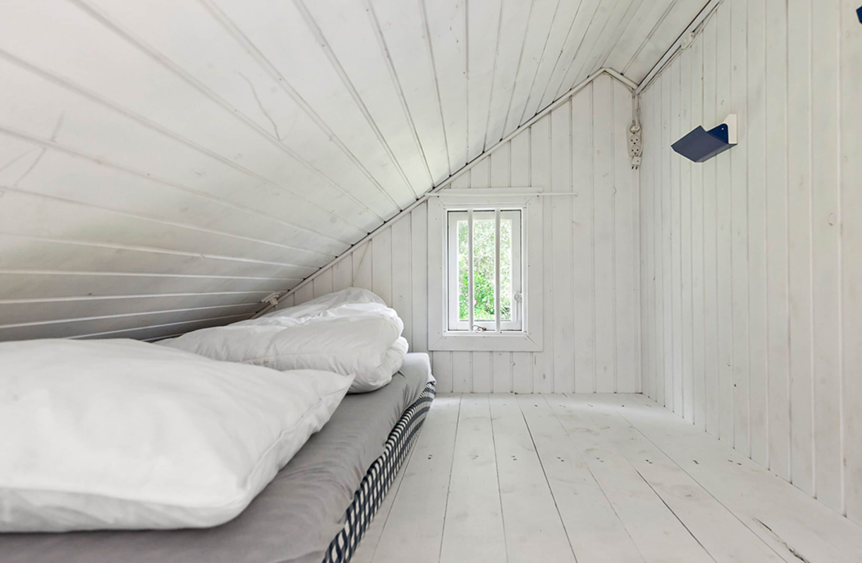 Una stanza con un letto, una finestra e pareti in legno.