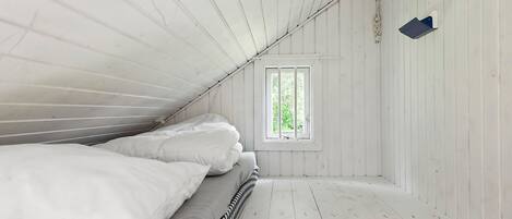 Una stanza con un letto, una finestra e pareti in legno.
