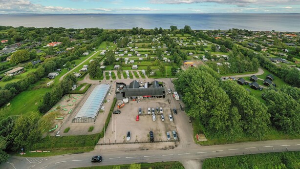 An aerial view of a residential area with a large building, parking lot, and a road.
