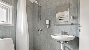A bathroom with a white sink, a mirror, a shower, and a toilet.