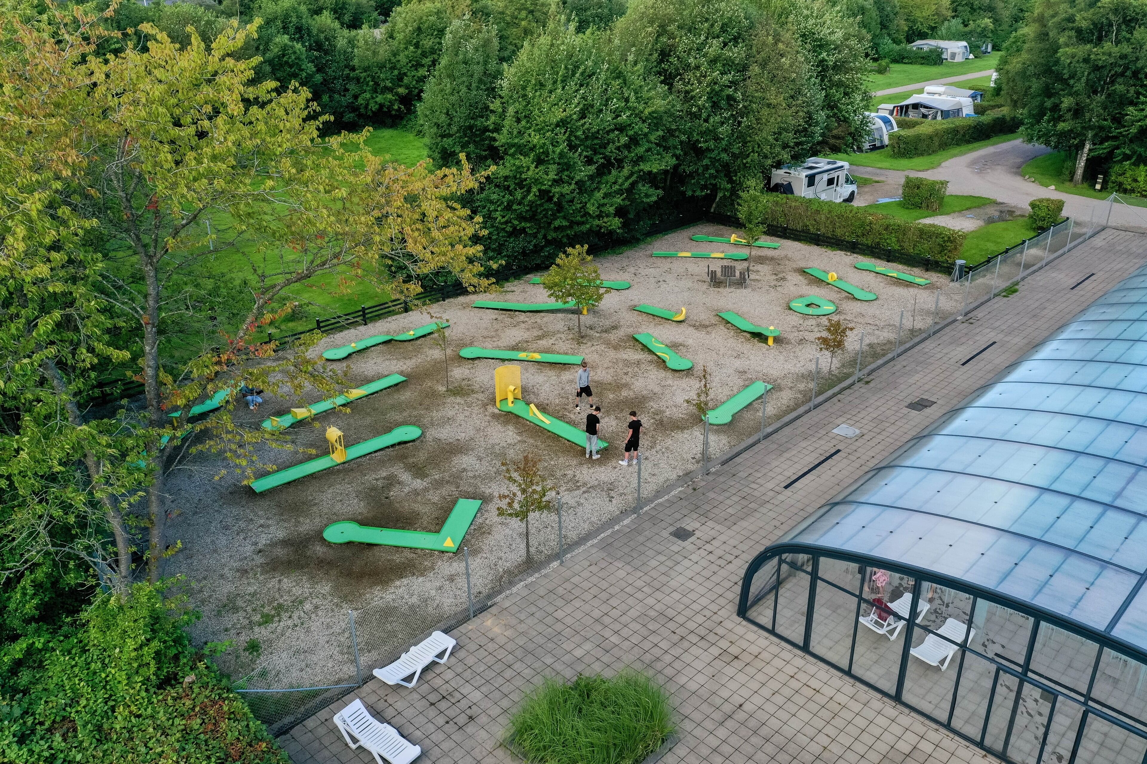 Ein Außenbereich mit Fitnessgeräten, einem überdachten Gang und einem umzäunten Spielbereich.