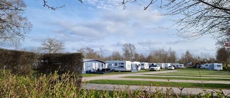 Un terrain de camping pour caravanes, avec plusieurs caravanes et un champ d’herbe.