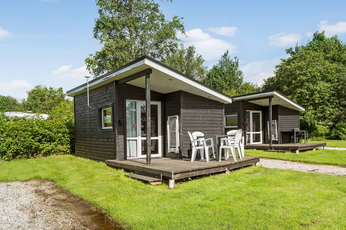 A two-story cabin with a deck and outdoor seating area.