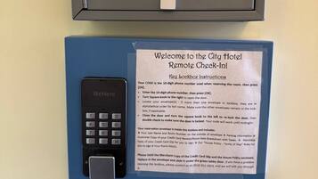 Uma caixa para depositar chaves, com um controle remoto e instruções para o processo de check-in remoto do Hotel City.