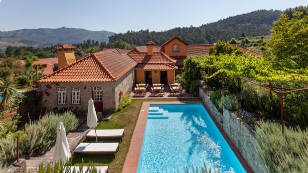 Une villa avec piscine, un espace extérieur aménagé et une vue sur les collines environnantes.