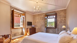 Une chambre avec un grand lit, une commode en bois et un téléviseur fixé au mur.