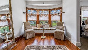 A bay window with two armchairs, a small table, and a decorative mirror. - Castle Manor Inn (Gloucester)