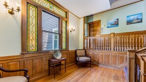 A wooden-paneled room with a staircase, a chair, and a table. - Castle Manor Inn (Gloucester)