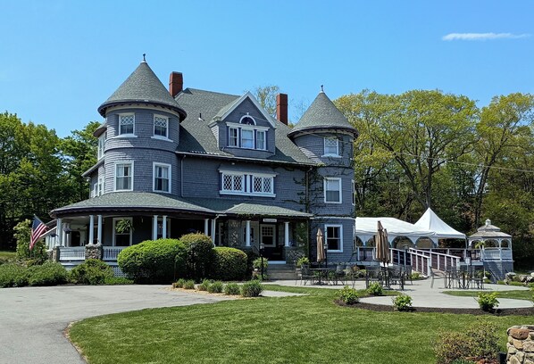 A large, historic house with multiple towers and a wrap-around porch.