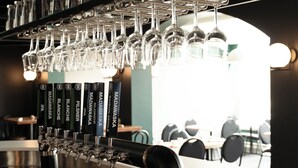A bar area with multiple taps and hanging wine glasses.