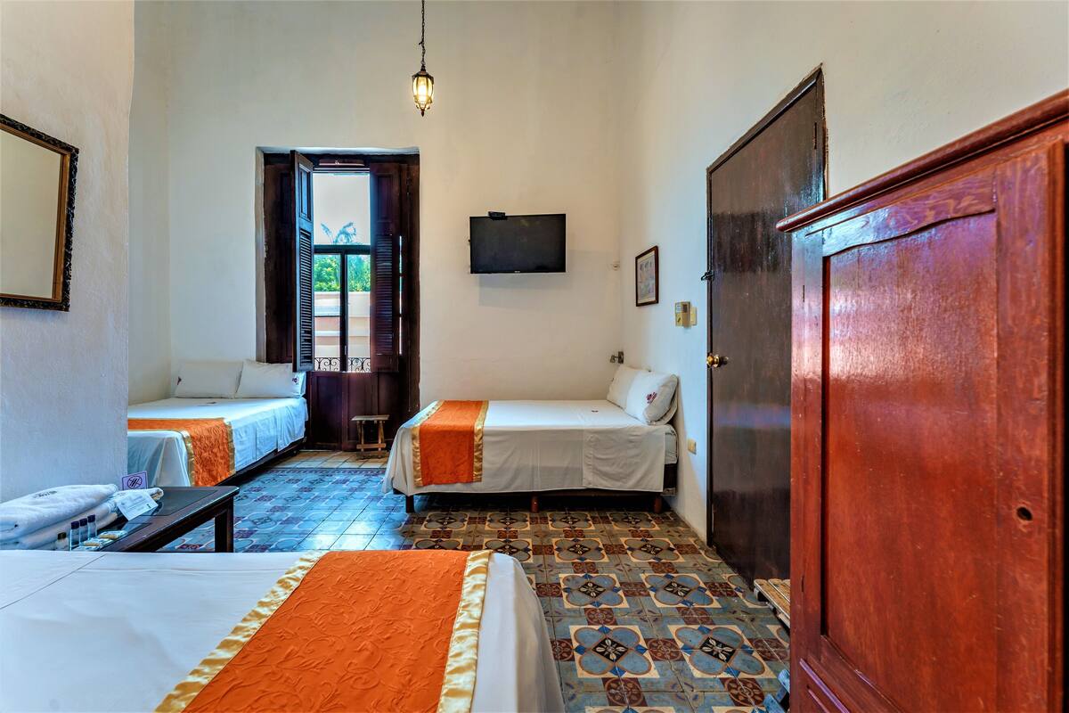 A hotel room with two beds, a television, and a wooden wardrobe.