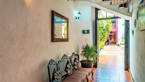 A corridor with a bench, a potted plant, and a staircase leading to an upper level. - Hotel Gran Centenario (Mérida)