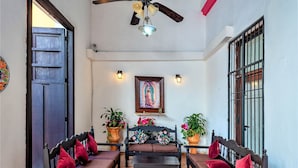 A covered patio with wooden furniture, a ceiling fan, and potted plants. - Hotel Gran Centenario (Mérida)