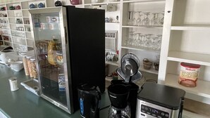 A kitchen area with a refrigerator, coffee maker, and a microwave. There are shelves with various kitchen items and a window above the counter. - Winsome Inn (St. Stephen)