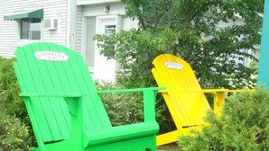 Two Adirondack chairs with 'Winsome Inn' signage, positioned in front of a white building with a green awning. - Winsome Inn (St. Stephen)