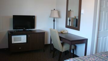 Une chambre d’hôtel équipée d’une télévision à écran plat, d’un bureau avec une lampe, d’un téléphone et d’un four à micro-ondes.
