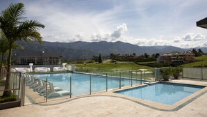 Un espace piscine avec des chaises longues et une vue sur les montagnes.