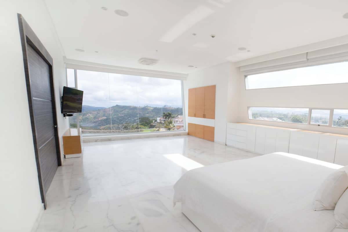 Un dormitorio con una cama grande, televisión y vistas a la ciudad.
