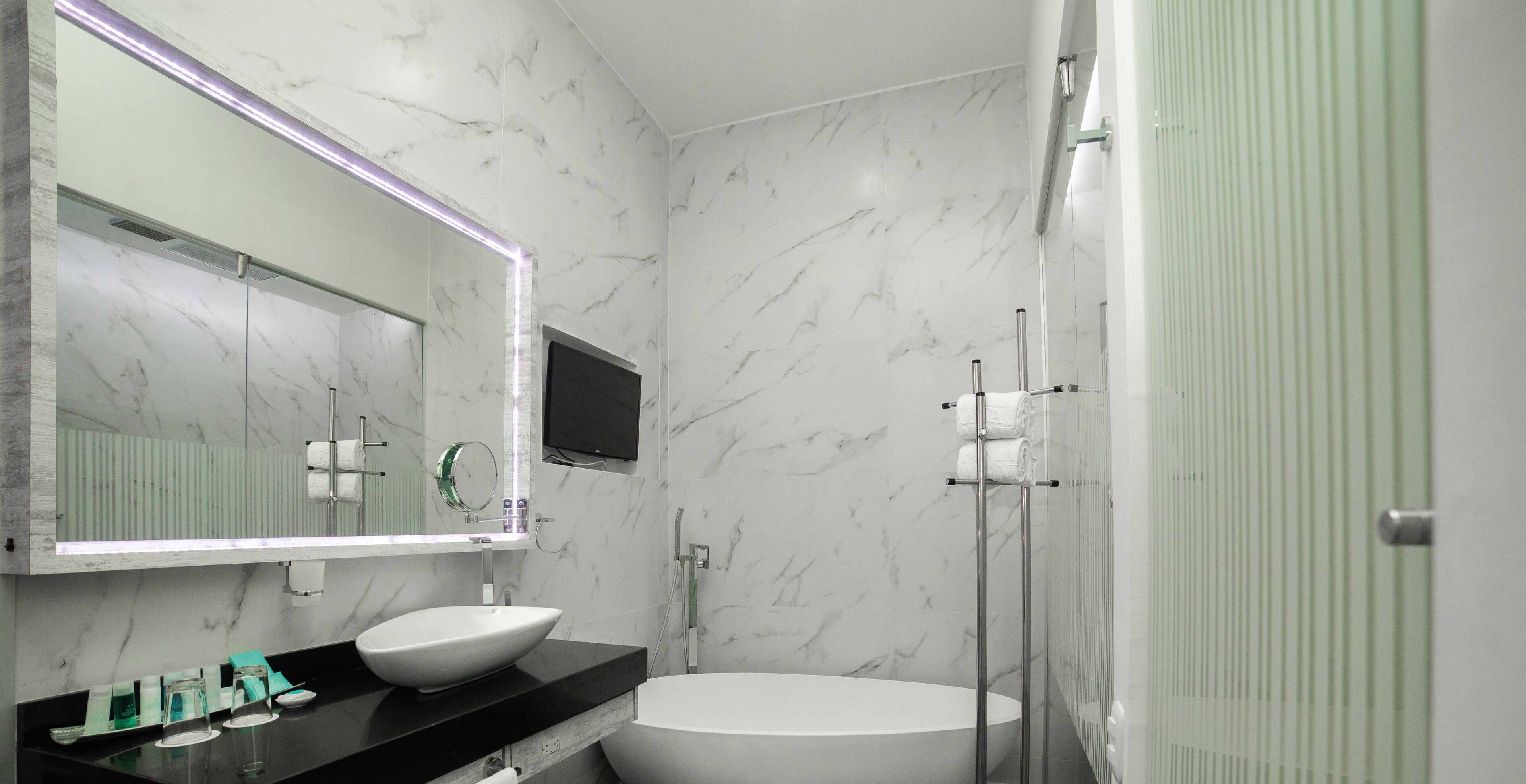 A modern bathroom with a large mirror, a white sink, and a freestanding bathtub.