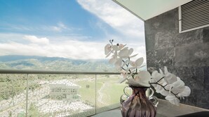 Un balcon offrant une vue sur des montagnes lointaines, un vase décoratif rempli de fleurs blanches et un mur à la texture intéressante.