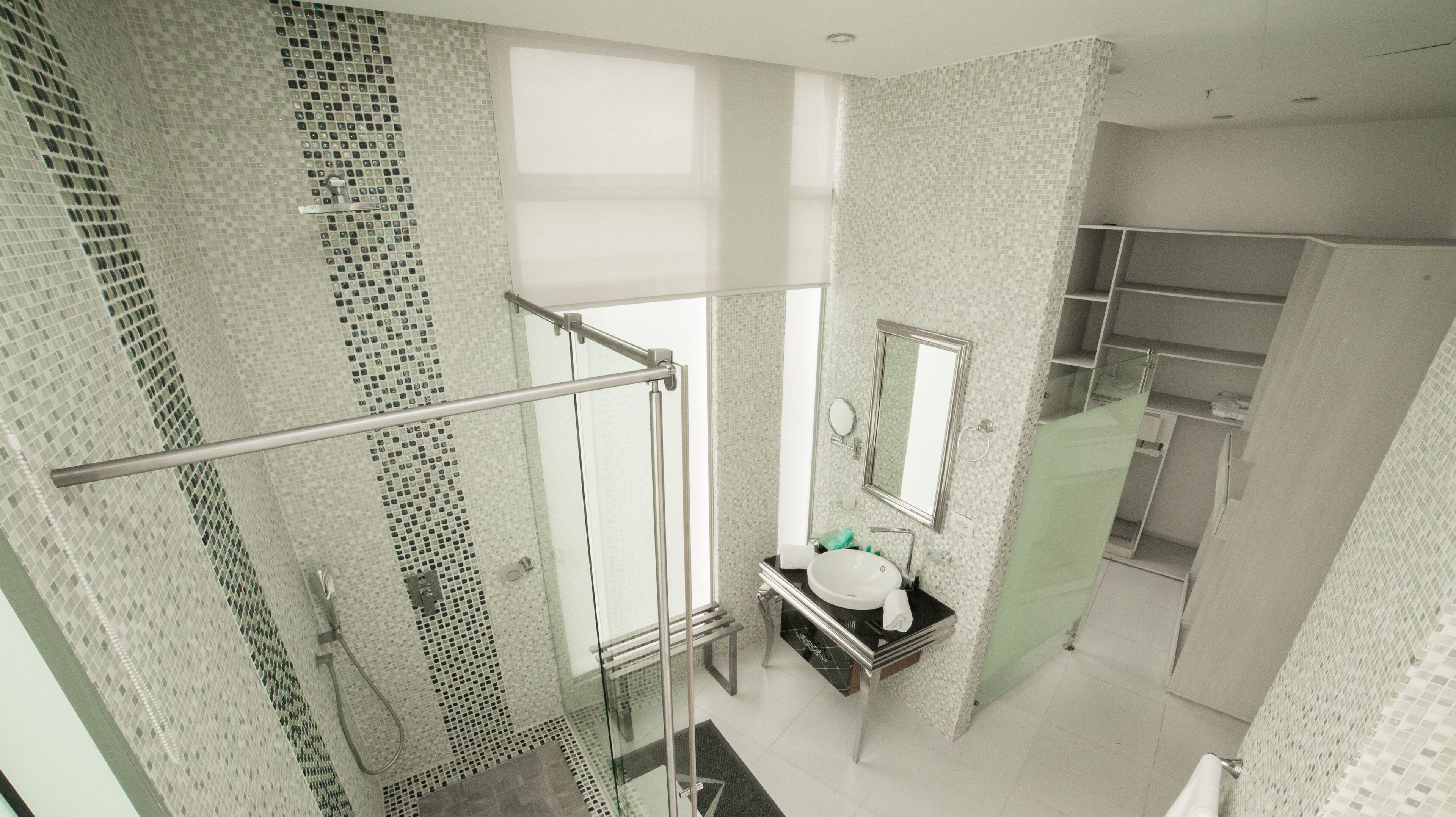Un baño moderno con cabina de ducha de vidrio, lavamanos con espejo y suelo de baldosas.