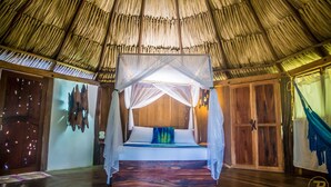 Una cama con dosel en una habitación con techo de paja.