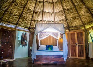 Una cama con dosel en una habitación con techo de paja.