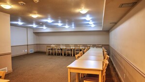Un salón de conferencias con una larga mesa, sillas, suelo alfombrado e iluminación en el techo.