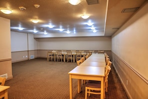 A conference room with a long table, chairs, carpeted floor, and ceiling lights.