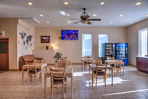 A hotel lobby with a dining area, a television, a map on the wall, and vending machines.
