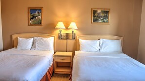Una habitación de hotel con dos camas, mesitas de noche, lámparas de pared y cuadros enmarcados.