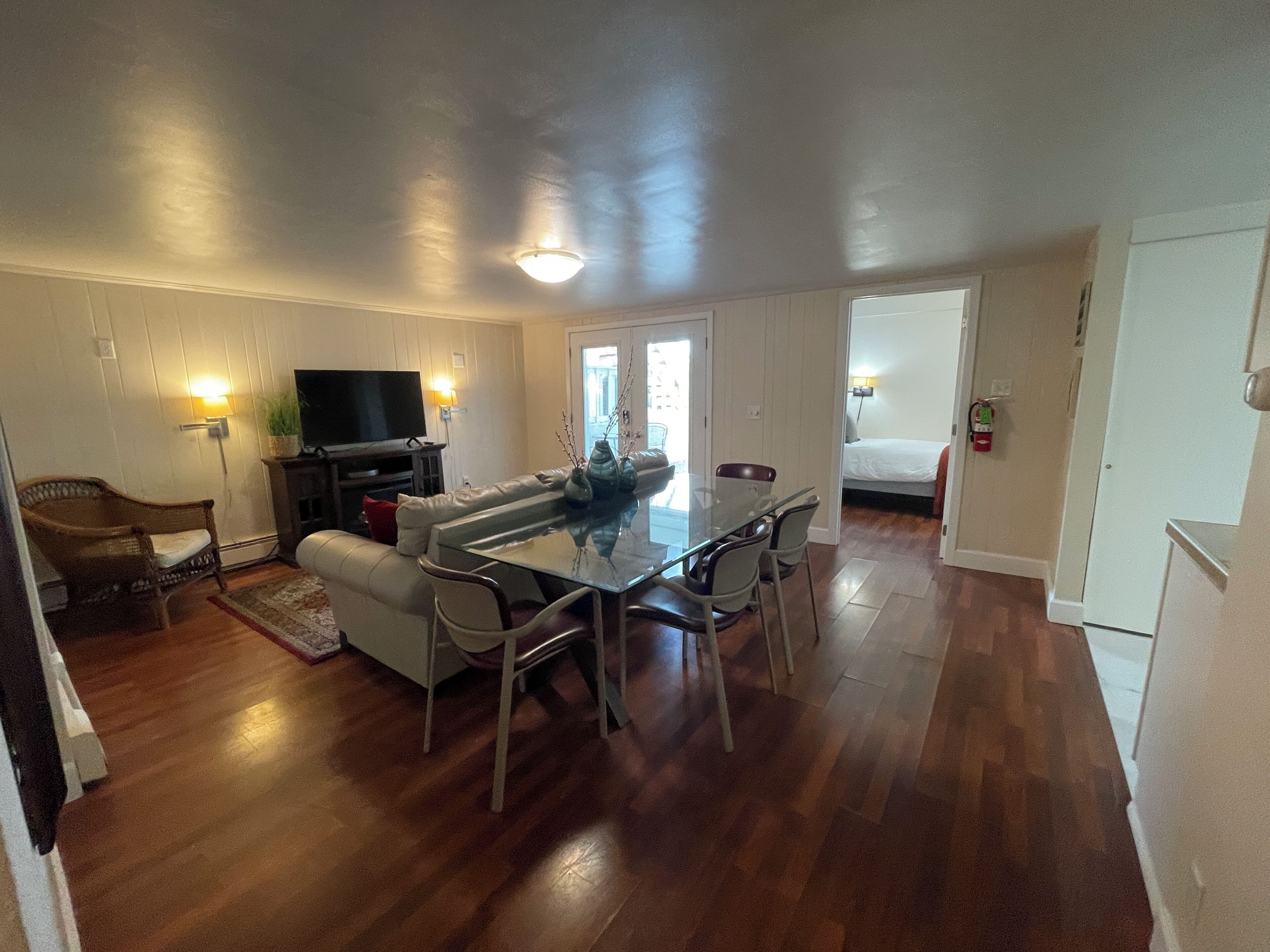 A compact living space with a dining area, a sofa, a TV, and a small kitchen area.
