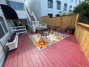 A wooden deck with a red floor, white railings, and a floral rug. - Arctic Fox Inn (Anchorage)