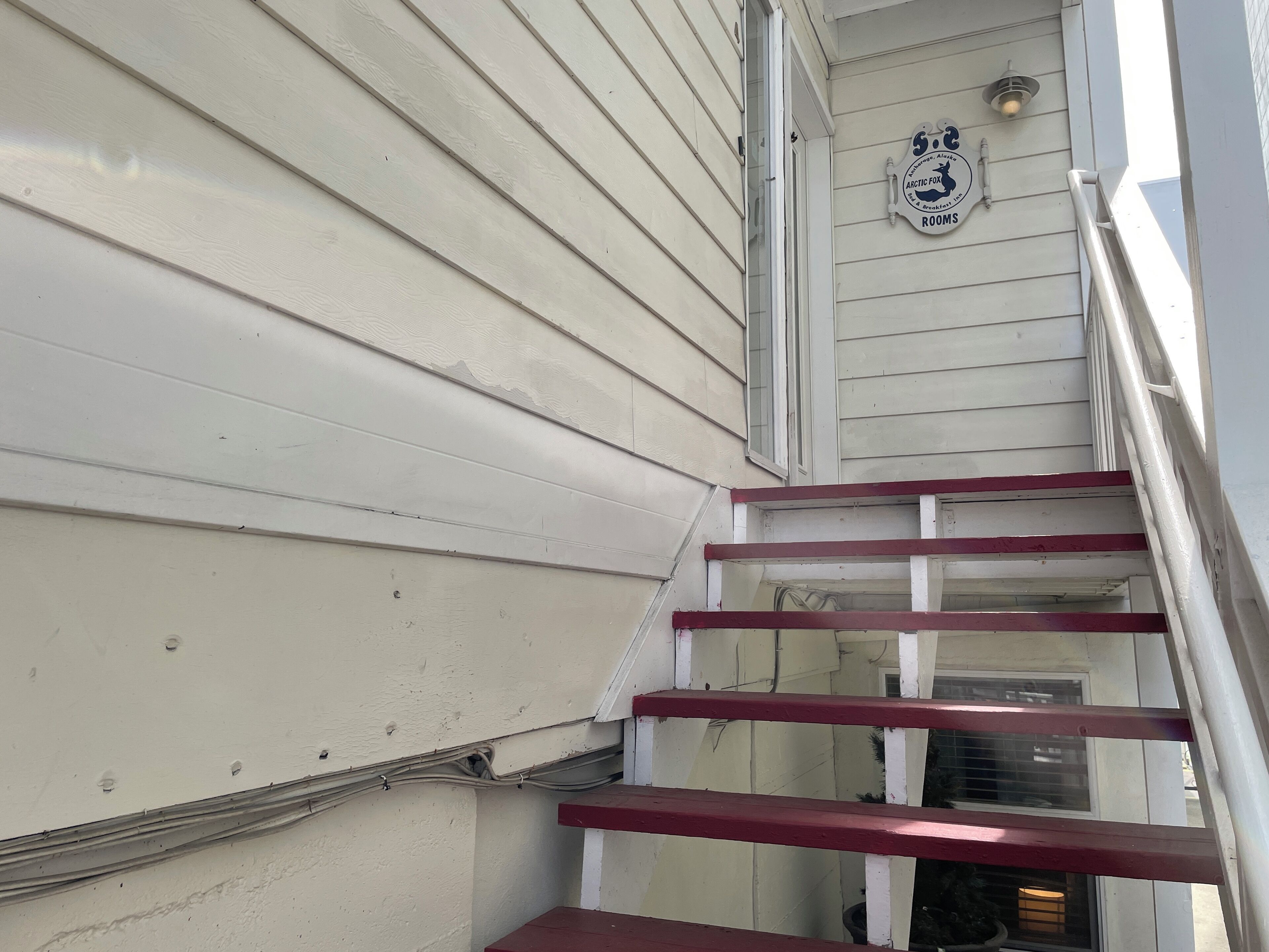 A white exterior with a red handrail and a sign that reads "ARCTIC FOX ROOM."