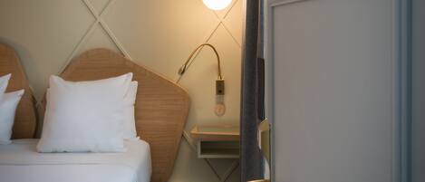 A hotel room with a bed, a nightstand, a lamp, and a door with the number 24.