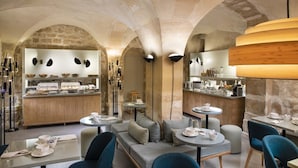 A restaurant with a stone arch ceiling, wooden furniture, and a buffet area. - Millésime Hôtel (Paris)