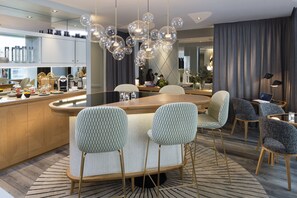 A modern kitchen with a central island, bar stools, and a dining area with chairs.